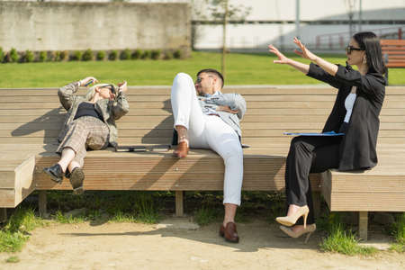 Three casual dressed business people are having a conversation while laying on the benchの写真素材