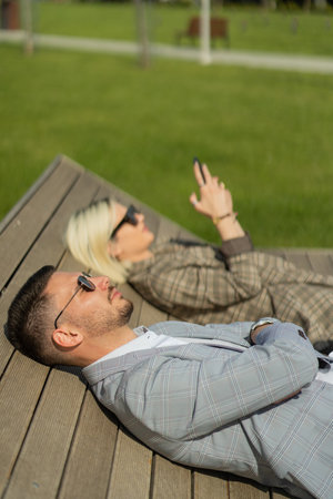 Three well suited business people are laying on the bench on their break from workの写真素材