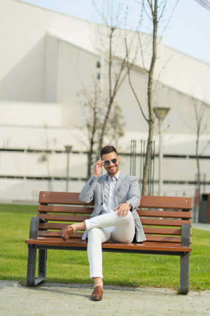 Urban businessman is sittin gon the bench and smilingの写真素材