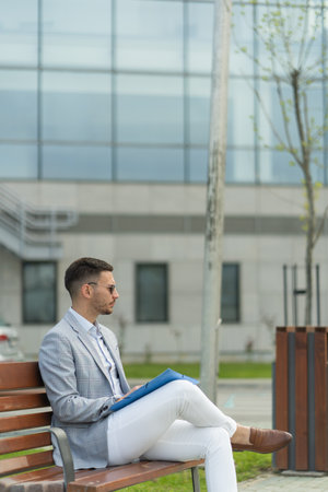 Handsome businessman is thinking about the plans while sitting on the benchの写真素材