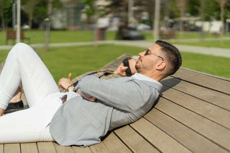 Well suited business co-workers are laying on the benchの写真素材