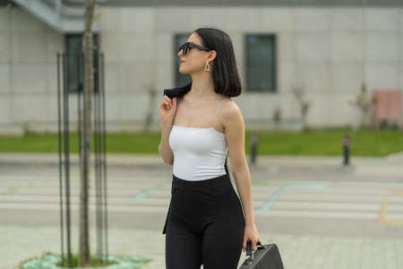 Attractive businesswoman is walking towards the company while holding her coatの写真素材