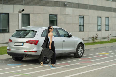 Beautiful businesswoman is going to get in her business carの写真素材