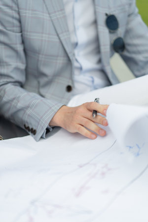 Perfect close up picture of hand working on hte blueprints for the companyの写真素材
