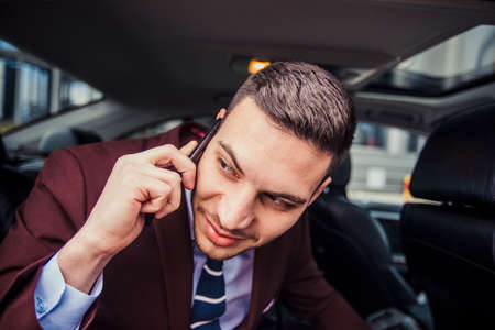 A young businessman is looking through a window in his stretch limoの写真素材