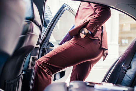 Handsome businessman holding lap top and getting in the limoの写真素材