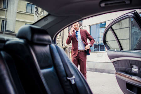 Man in suit is driving in a car and talking on cell phoneの写真素材