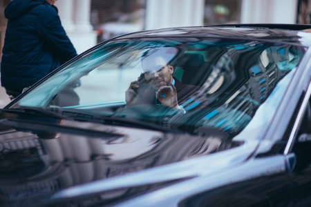 Serious businessman sitting at the front seat in his limo on a busy city street.の写真素材