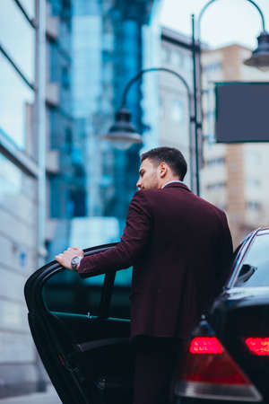 Handsome businessman entering and exiting his limo while looking sharp and serious.の写真素材