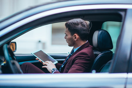 A manager sitting at the front seat of his limo talking on his cellphone while making a lot of hand gestures.の写真素材
