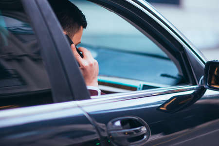 A serious businessman is having a conversation on his phone while looking sharp with his suit and tie.の写真素材