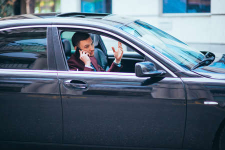 A serious businessman is having a conversation on his phone while looking sharp with his suit and...
