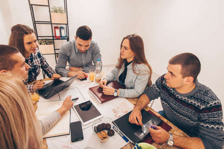 Group of young people disscusing on the table on their workplaceの写真素材