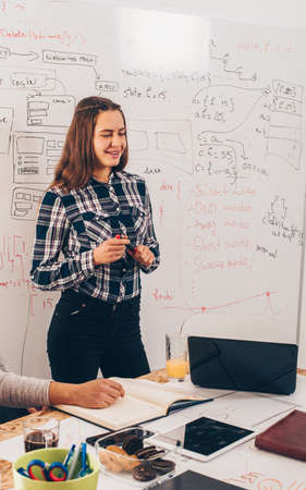 Group of young people disscusing and writing on the board on their workplaceの写真素材