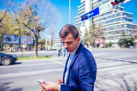 A businessman has parked his car at the side of the boulevard while he checks his car oil, on a...