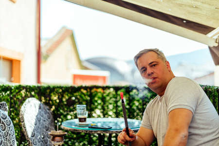 Urban businessman looking at his smartphone while sitting on balcony