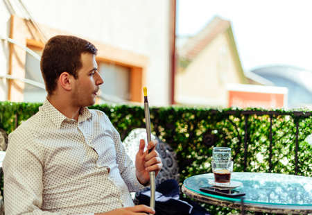 Man on building terrace smoke hookah and enjoying in the viewの写真素材
