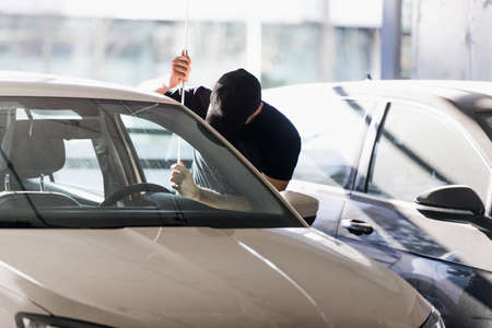 Thief is standing on the parking and trying to break a car doorの写真素材