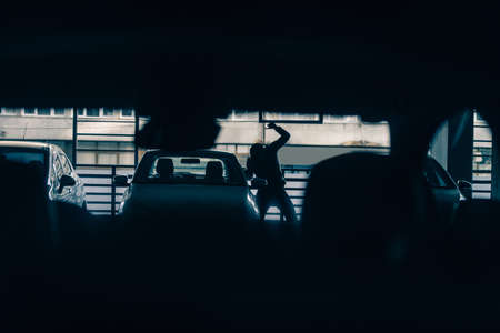 A thief is robbing a car on the parking while holding crowbar toolの写真素材