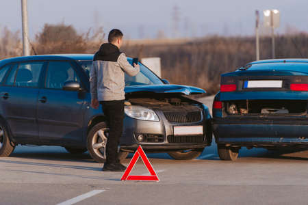 Young man taking picture of his damaged car after traffic collisionの写真素材