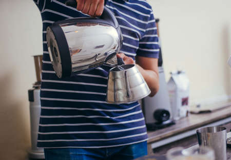 Male barista using a coffee maker to make a nice cup of coffee. Cafe worker preparing a coffeeの写真素材