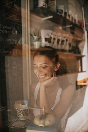 Closeup portrait of a gorgeous young brunette woman holding cup of coffeeの写真素材