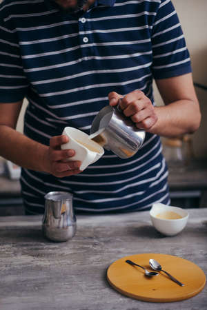 Hand of barista making latte or cappuccino coffee pouring milk making latte artの写真素材