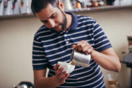Professional barista pouring latte foame over coffee, espresso and creating a perfect cappuccinoの写真素材