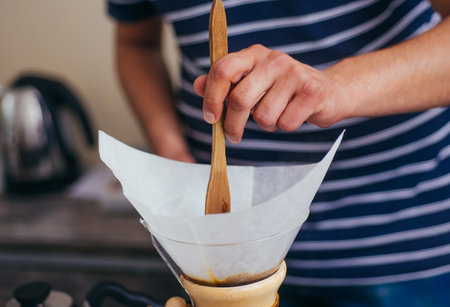 Indoor shot of young male barista making a cup of coffee while standing behind cafe counterの写真素材