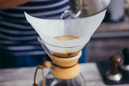 Expert barista close up hands preparing delicious coffee while pouring hot water into the filterの写真素材