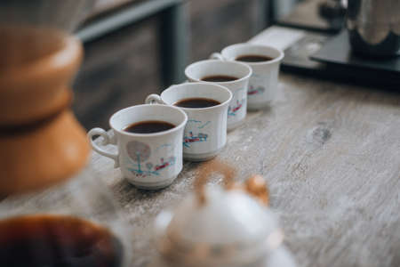 Modern white ceramic cups with freshly made espresso sitting on a wooden counterの写真素材