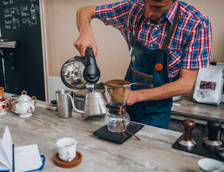 Handsome barista driping hot water into coffee at the coffee shopの写真素材
