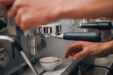 A close-up of making espresso, the coffee is poured into white ceramic cupの写真素材