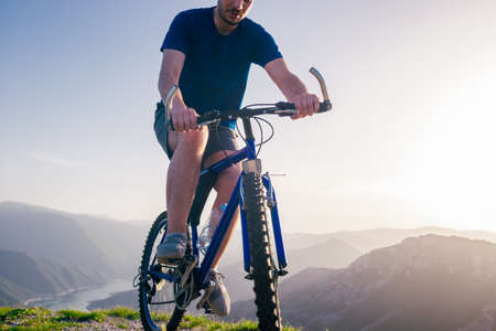 Close up photo from a mountain biker riding his bike ( bicycle) on rough rocky terrain on top of a mountain, wearing no safety equipment. Adrenalin junkie.の写真素材