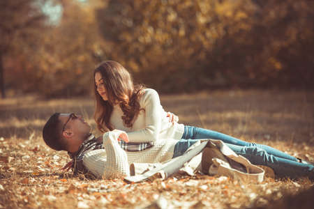 Cute couple is lying on the ground in the park on the colorful autumn leavesの写真素材