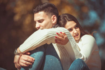 Young stylish couple is in the park, smiling and having fun together while sitting on the grassの写真素材