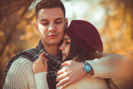 Stunning couple is spending autumn day together, enjoying the nature while hugging each other