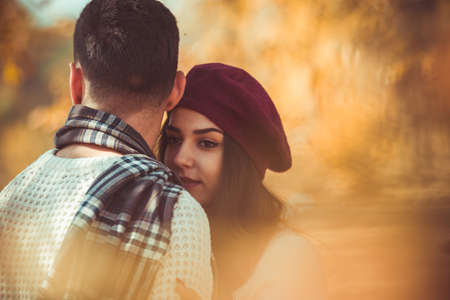 Couple in love is hugging white standing next to the tree, looking happy and satisfiedの写真素材