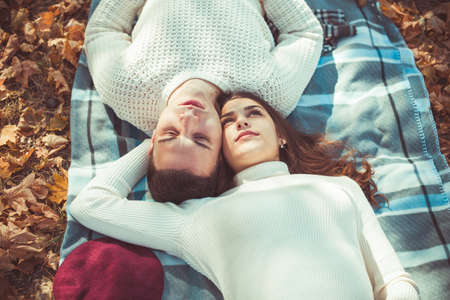 Splendid couple is spending autumn day in the park, lying on a blanket and huggingの写真素材