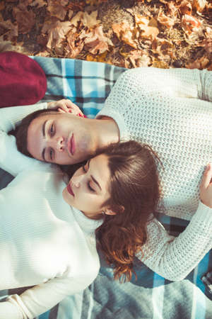Wonderful couple is lying head to head in the park and enjoying the autumn together