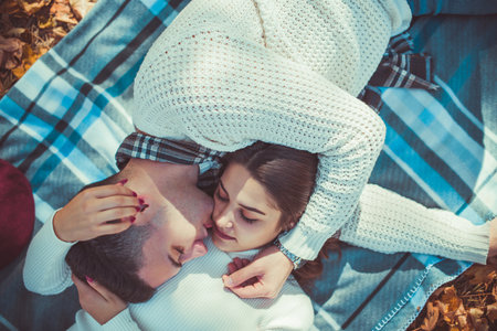 Attractive couple wearing white is lying in the park, hugging and looking at each otherの写真素材