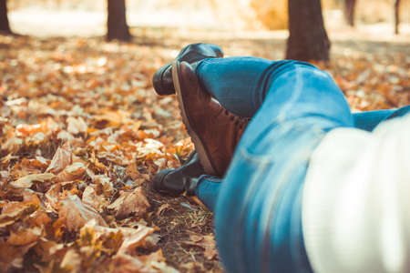 Modern couple wearing jeans is lying in the park with crossed legsの写真素材