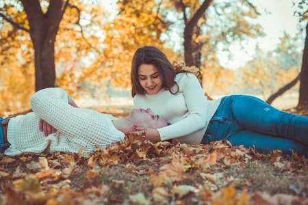 Beautiful couple is enjoying the autumn in the park, lying on autumn leaves and looking satisfiedの写真素材