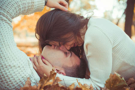 Charming couple is spending carefree time in the park, lying on the grass and kissingの写真素材