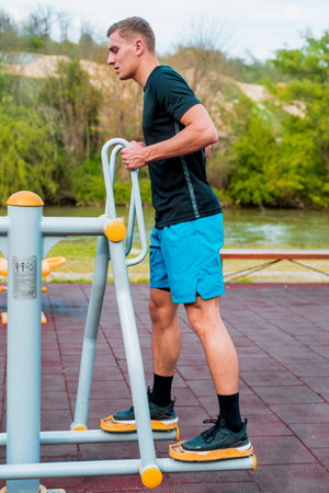 Crossfit man doinglegs exercise on gazelle exercise machine during workout outdoorsの写真素材