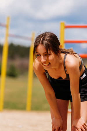 A young woman is doing pull ups in the park