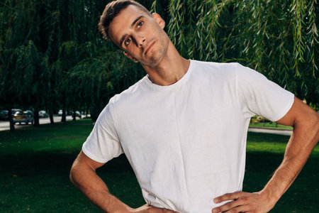 An athletic man with a muscular body in a sporty suit doing crossfit on a natural background