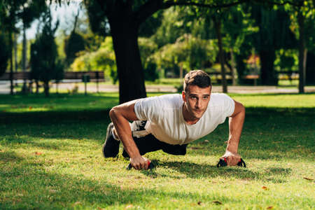 Fitness gym push up exercise man doing shoulder press workout for training muscles outdoor on meadow...