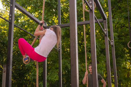 Handsome guy is watching his attractive girl climbing the rope