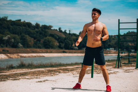 Shirtless sportsman stretching muscles on the beachの写真素材
